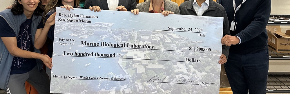 People holding a big check made out to MBL for 200,000 dollars.