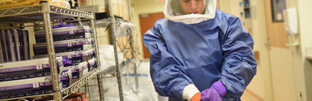 A medical worker dons personal protective equipment. 
