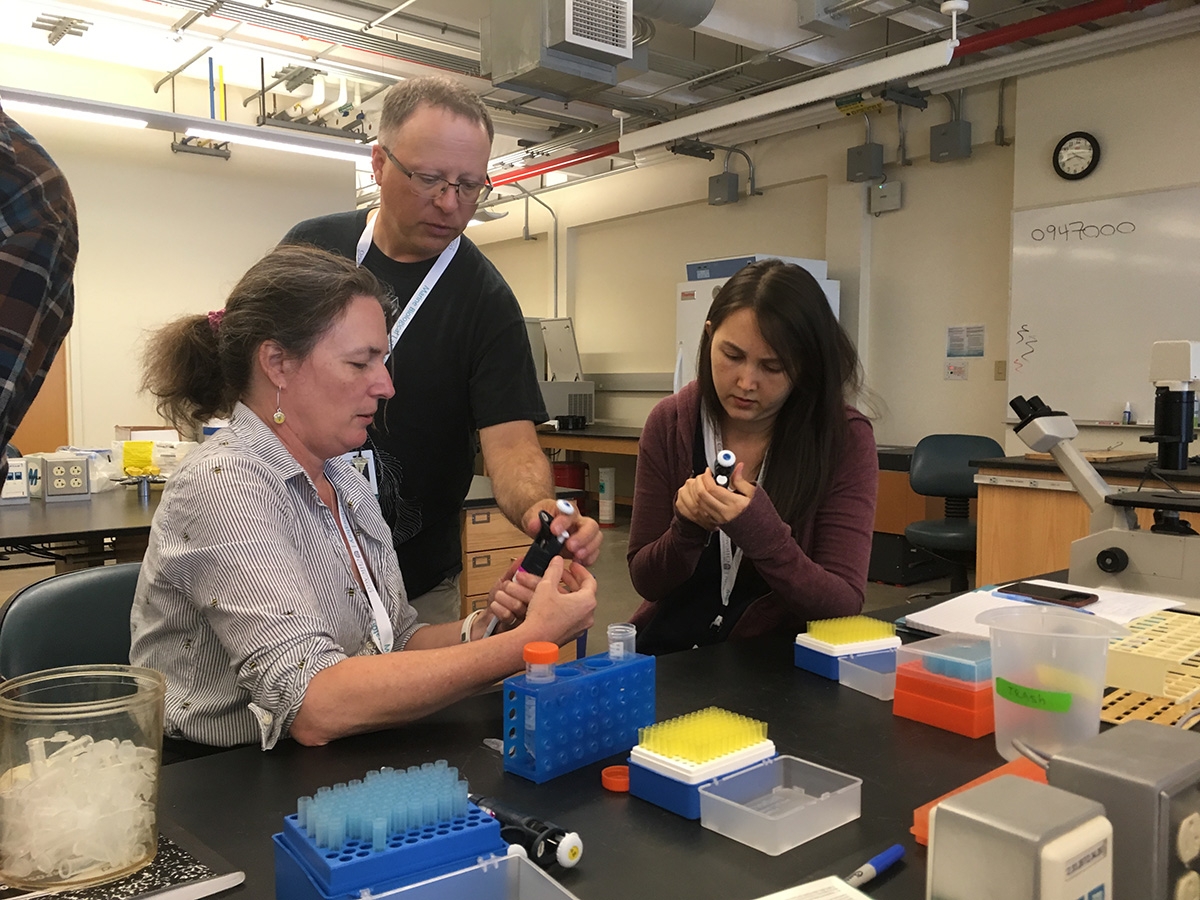 Charles "Brad" Shuster of New Mexico State University and co-director of the Biomedical Hands-On Research Course, shows 2018 fellows Macon Morehouse, left, and Shayla Love, right, techniques for micropipetting. 