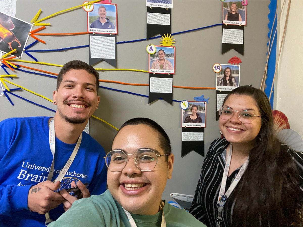 John Gonzalez-Amoretti (left), Yesenia Garcia-Sifuentes (center), and Almarely L. Berrios-Negron (right) stand in front of the SPINES bulletin board.