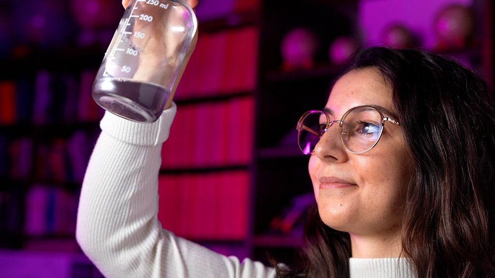 Ligia Coelho looking at content in a beaker